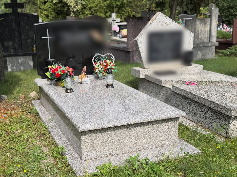 Nagrobek z jasnego granitu z czarną tablicą na Cmentarzu Północnym, napisy rozmyte